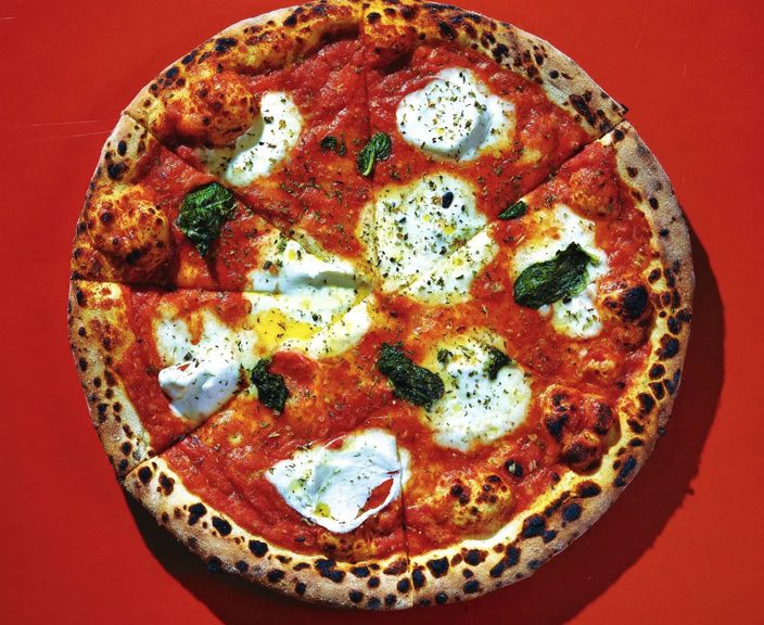 A whole margherita pizza with melted mozzarella and basil