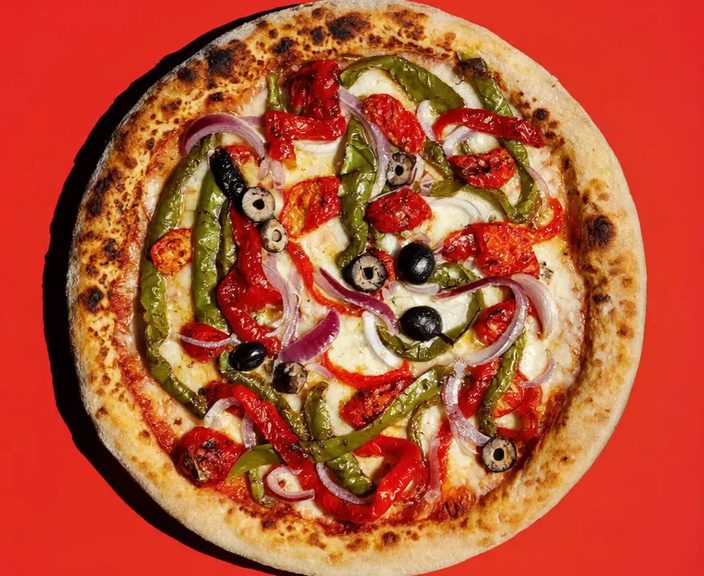 A whole vegetable pizza with peppers, olives and red onion