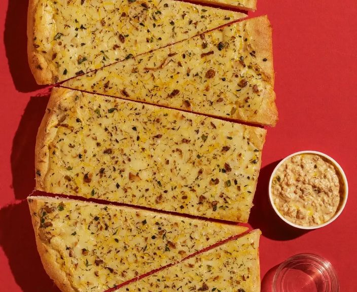 Garlic pizza bread cut into strips with a pot of dip