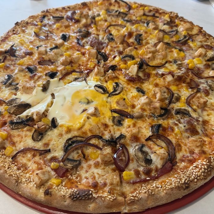 Pizza with fried egg, sweetcorn, aubergine and onion